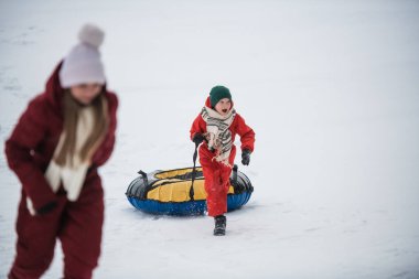İki çocuk, bir erkek ve bir kız tüplerini yukarı çekerek aşağı yuvarlandılar.