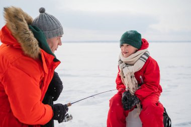 Baba ve oğul kışın kırmızı elbiseleriyle nehir kıyısında balık tutmaya gelirlerdi.
