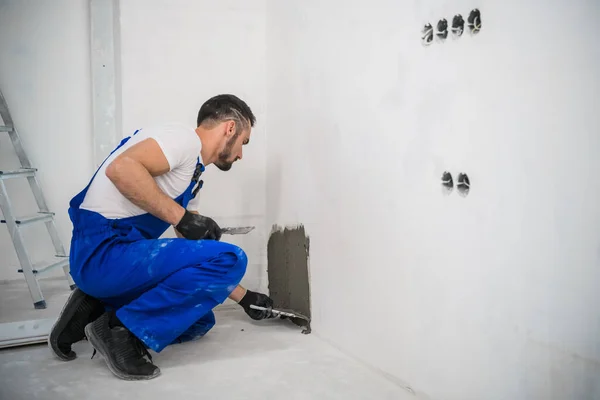 Een reparateur brengt cement aan op de muur om de tegels te bevestigen — Stockfoto