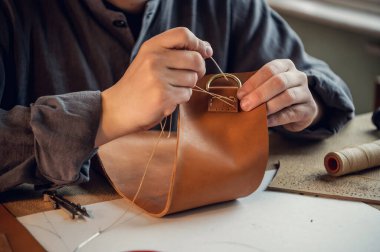 Yakından çekilen fotoğrafta yetenekli bir ayakkabıcının elleri gerçek bir deri parçasından çanta yapar.