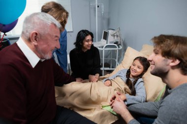 Hastane koğuşunda yatmakta olan güzel, küçük bir kızı ziyaret eden bir aile.