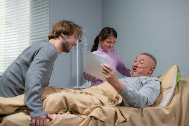 Yaşlı ve mutlu bir adam torununun onu hastaneye getirdiği resme hayran.