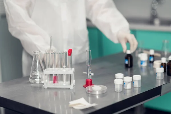Feche o quadro de uma mesa de laboratório com as mãos enluvadas de um funcionário que executa alguma pesquisa — Fotografia de Stock