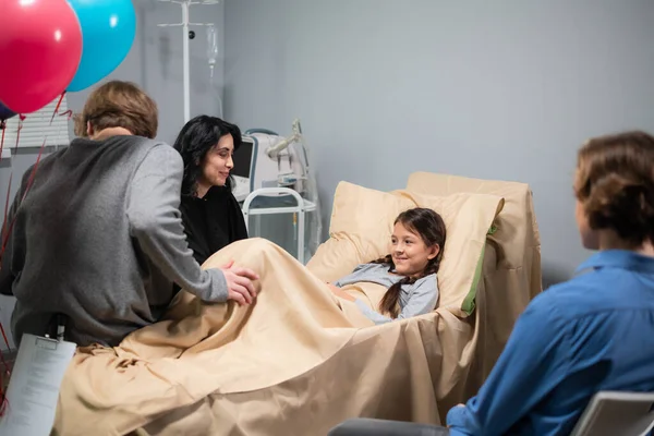 Kazadan sonra güzel, küçük bir kızı ziyarete gelen bir aile. Kız hastanede yatıyor.