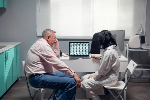 Paciente sênior e um radiologista com um raio-x olhando para o monitor do laptop em um hospital — Fotografia de Stock