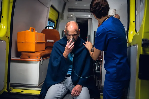 Un blessé dans une couverture reçoit les premiers soins dans une ambulance. — Photo