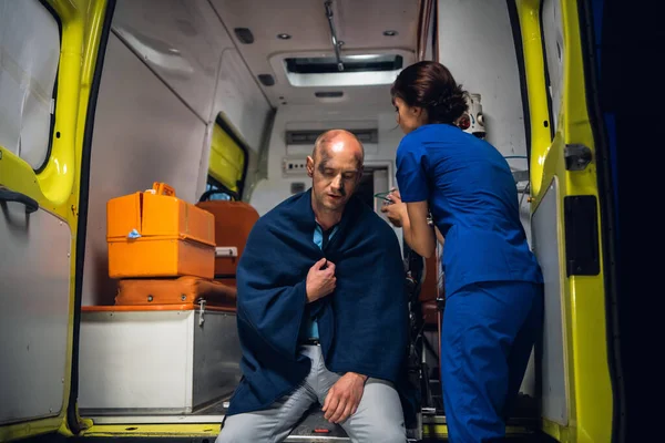 Женщина-парамедик, оказывающая первую помощь раненому мужчине, спасенному из огня — стоковое фото