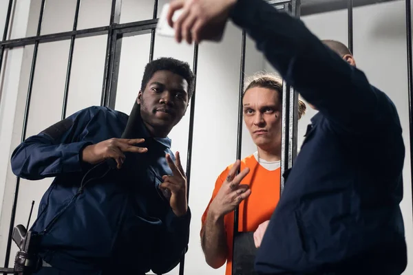 Atores no set de um filme sobre a prisão fazem uma selfie engraçada em uma cela de prisão contra o fundo de bares. — Fotografia de Stock