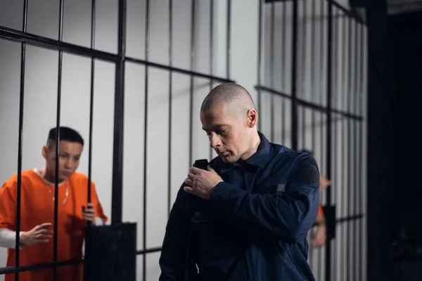 Uniformovaný dozorce v asijské věznici podnikne večerní prohlídku cel s vězni. — Stock fotografie