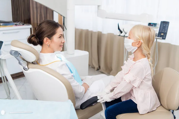 Een meisje doet alsof ze een dokter is in een tandheelkundige kliniek, een echte d — Stockfoto