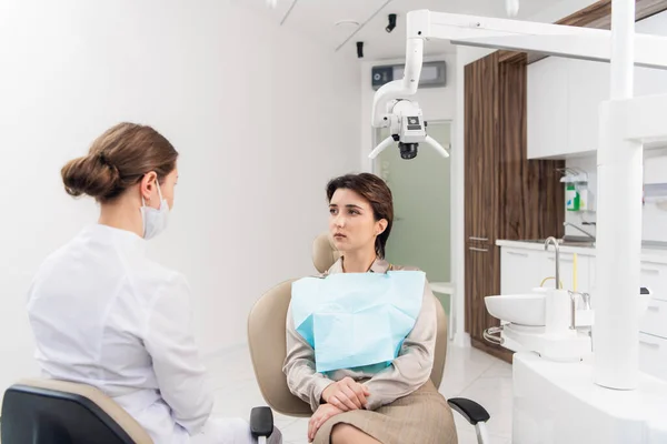 Молодая женщина разговаривает со своим дантистом в стоматологической клинике — стоковое фото