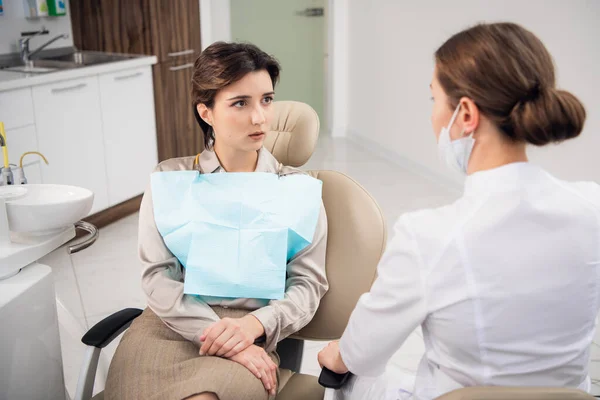 Un joven dentista consultando a su paciente en la clínica — Foto de Stock