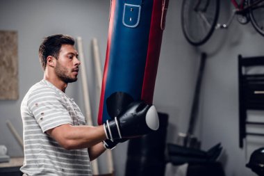 Genç bir sporcu garajında kum torbasıyla antrenman yapıyor..