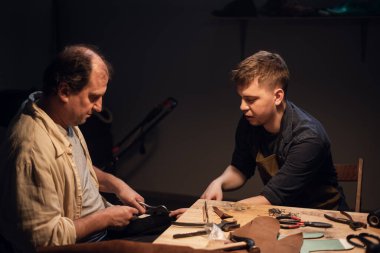 Baba ve oğul, anne için bir hediye hazırlayın. Ayakkabıcıda hevesle ayakkabı yapın..