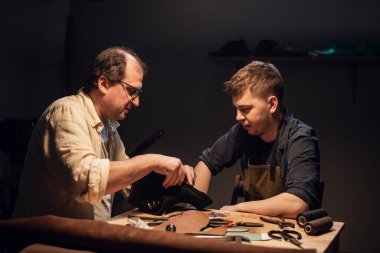 Yaşlı bir kunduracı ve çırağı atölyelerinde çeşitli aletlerle el yapımı ayakkabılar yapıyorlar..