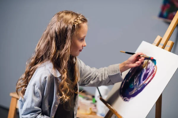 Una niña de vacaciones en su habitación dibuja una pintura al óleo. Una artista apasionada por su hobby. — Foto de Stock