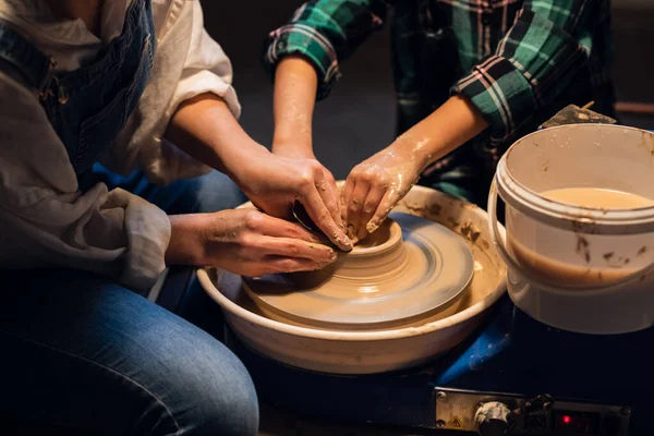 A young female potter teaches a small boy to make a pot of clay. — Stock Photo, Image