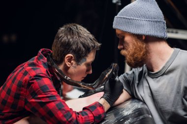 Dövme salonunun müşterisine göre genç bir sanatçı koluna sopa ve dürtme metodu kullanarak acısız bir dövme yapıyor..