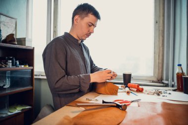 Bir ayakkabı atölyesinde, bir bronzlaştırıcı çekiç ve diğer aletlerle el yapımı ayakkabılar yapar.