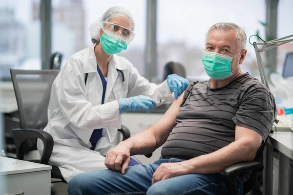 Yaşlı bir adam klinikte kovid 19 koronavirüse karşı aşı oluyor. Nüfusun evrensel aşılanması