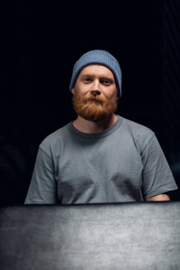 Örgü şapkalı, kızıl sakallı, hippi bir adamın siyah arka planında portresi..