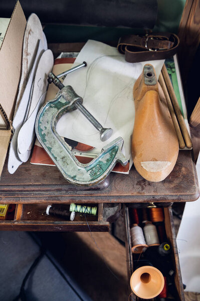 On a wooden table in the shoe workshop are insoles, blanks for shoes, fasteners, belts and other working tools