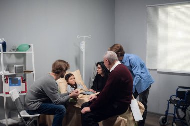 Hastane ziyareti sırasında küçük bir kızı teselli eden bir aile.