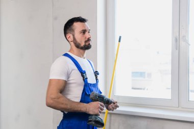 Tulumlu ustabaşı elinde mezurayla.