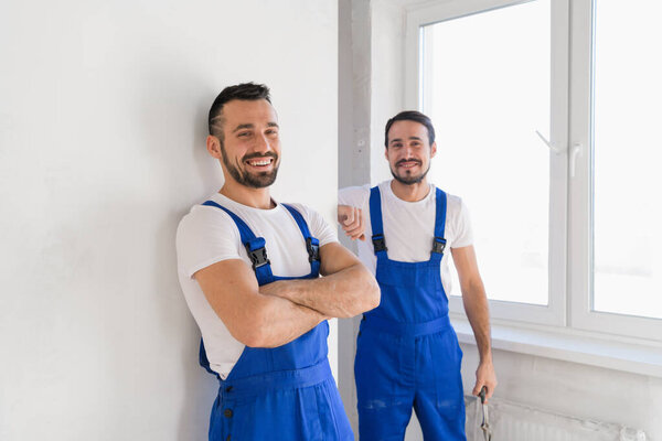 Два строителя в комбинезоне смотрят в камеру
