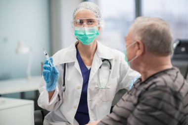 Nüfusu covid 19 virüsüne karşı aşılama programı. Bir hemşire yetişkin bir erkeğin koluna iğne yapar.