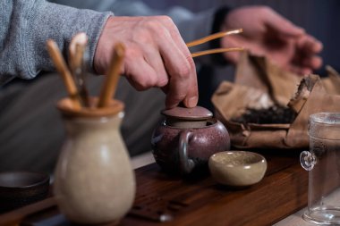 Erkekler özel bambu toka yapraklarını tepsiden yapılmış seramik çaydanlığa koyar. Çin çayı yapma süreci..