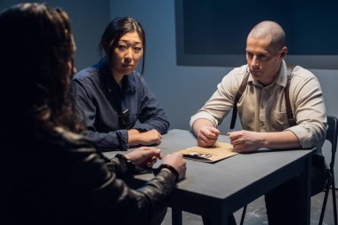 Araştırmacı bir sorgulama yapıyor, şüpheli suç ortaklarının fotoğraflarını gösteriyor.