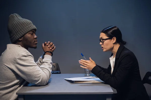 A black guy listens to his rights from a civil lawyer at a table in a visiting room in a state prison