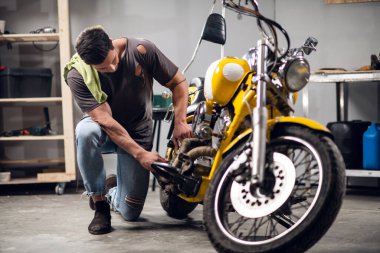 Otomobil tamirhanesinde motosiklet ayarlayan genç bir tamirci. Hobiler ve iş etkinlikleri.