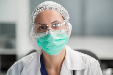 Ofisinde maske ve gözlük takan sevimli bir kadın doktor poz veriyor.