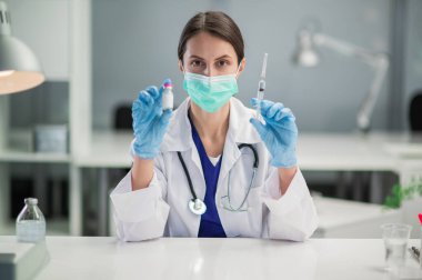 Hastanenin tedavi odasında, bir hemşire elinde bir aşı tutarak kovid 19 'a karşı halkı aşılamaya hazırlanıyor.