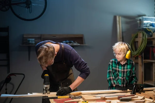 Deneyimli bir marangoz ve genç çırağı atölyelerinde ahşap işçiliği yapıyorlar..