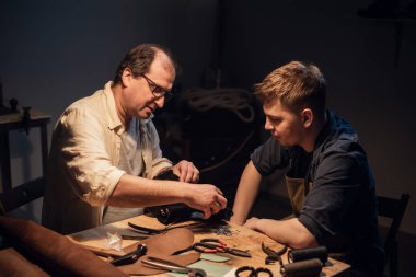 Baba ve oğul, anne için bir hediye hazırlayın. Ayakkabıcıda hevesle ayakkabı yapın..