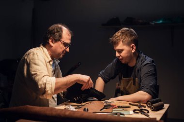 Saygıdeğer yaşlı bir kunduracı, özel bir atölyede genç bir çocuk için el yapımı ayakkabılar konusunda yüksek lisans dersi veriyor..