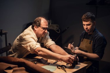 Saygıdeğer yaşlı bir kunduracı, özel bir atölyede genç bir çocuk için el yapımı ayakkabılar konusunda yüksek lisans dersi veriyor..