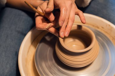 Çamur ve aletlerle vazo yontan genç bir kızın güzel elleri..