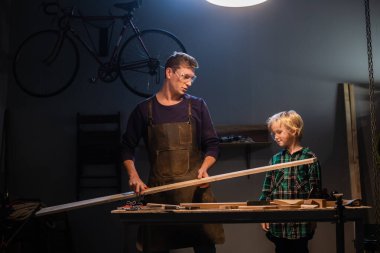 Kardeşler anneleri için garajda tahtadan bir hediye hazırlayın..