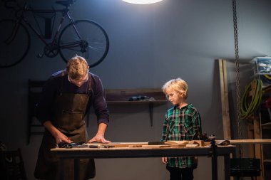 Deneyimli bir marangoz ve genç çırağı atölyelerinde ahşap işçiliği yapıyorlar..