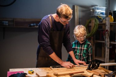 Deneyimli bir marangoz ve genç çırağı atölyelerinde ahşap işçiliği yapıyorlar..