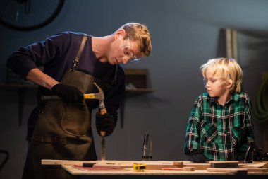 Kardeşler anneleri için garajda tahtadan bir hediye hazırlayın..