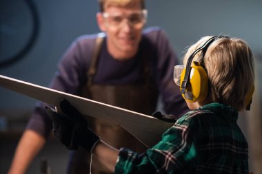 Ağabeyi küçük olana tahtadan silah yapmasında yardım etti ve küçük olan da marangozhanede oynuyor..