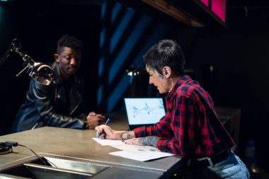 Dövme salonu sahibi genç bir sanatçı dövme yaptırmak isteyen siyahi bir müşterisinin resmini çiziyor..