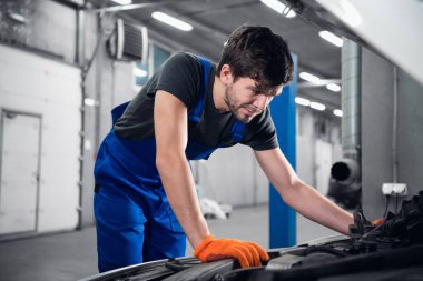 Atölye çalışanı arabanın kaputunun altına bakıyor.