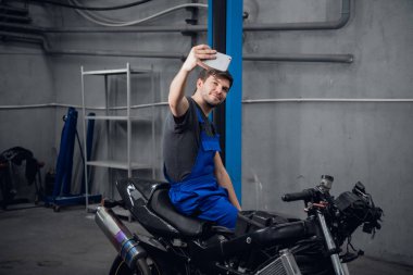 Bir işçi motosikletle fotoğraf çeker.