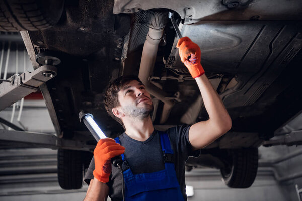 A worker lights up the car bottom with a gadget
